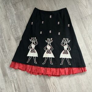 A-line midi skirt with white and red embroidered figures and a ruffled red hem.